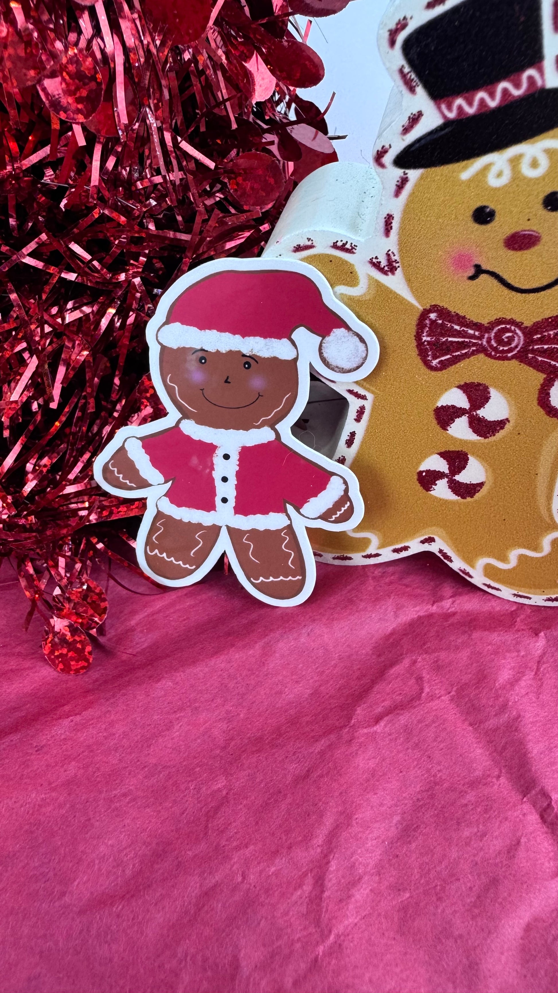 Close-up of laminated gingerbread man sticker dressed like Santa, showing hand drawn details and smooth finish.