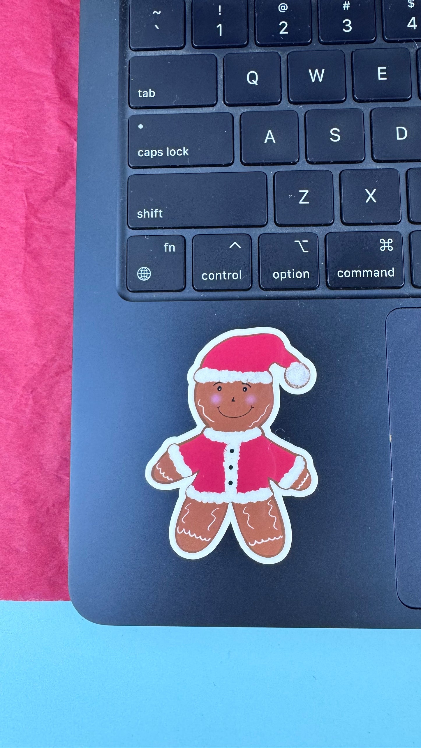 Hand drawn gingerbread Santa sticker applied to a laptop, showing how the laminated sticker looks in use.