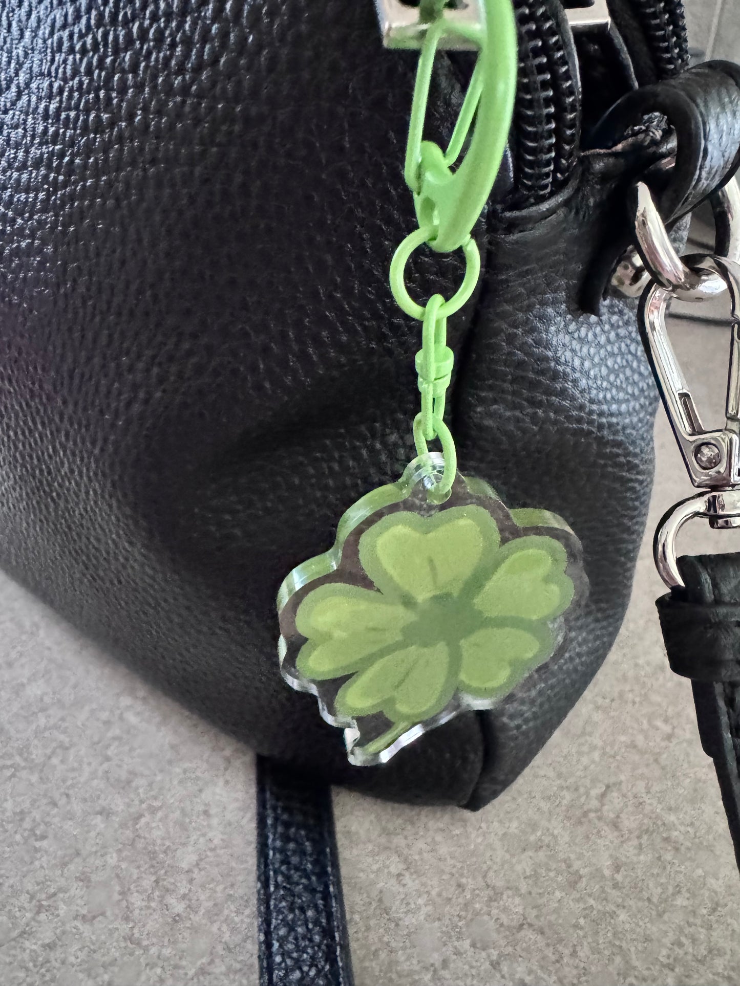 Green four-leaf clover keychain attached to a black leather bag.