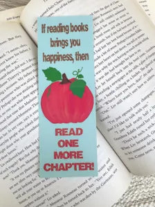 A rectangular fall bookmark with a hand drawn pumpkin in the center with the text "If reading books brings you happiness, then read one more chapter"